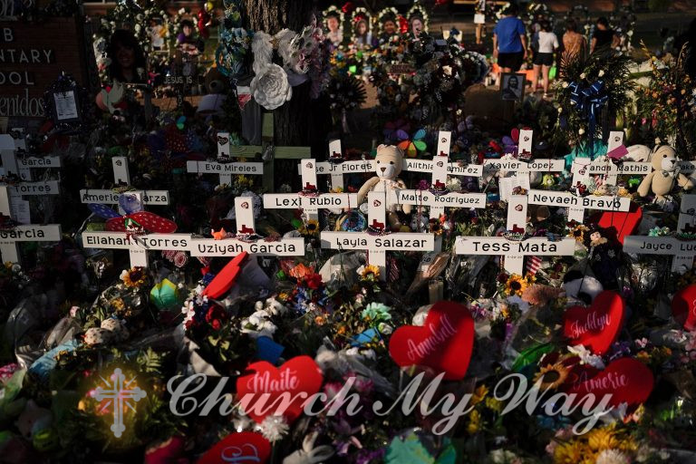 Flowers are piled around crosses with the names of the victims killed in last week